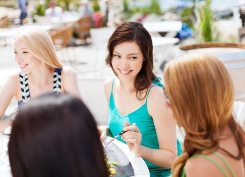 summer holidays and vacation - girls eating and drinking in cafe on the beach