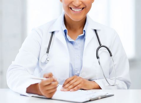 healthcare and medical concept - female doctor with stethoscope writing prescription