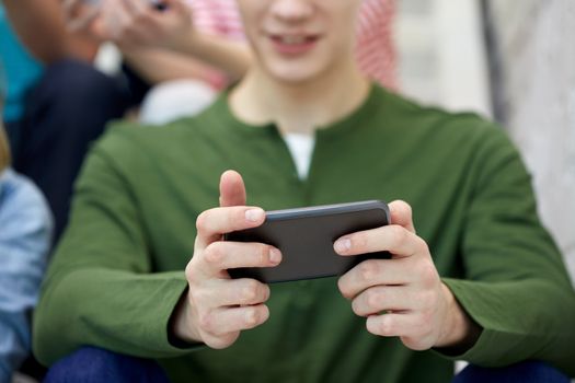 people, technology and internet concept - close up of young man with smartphone at school