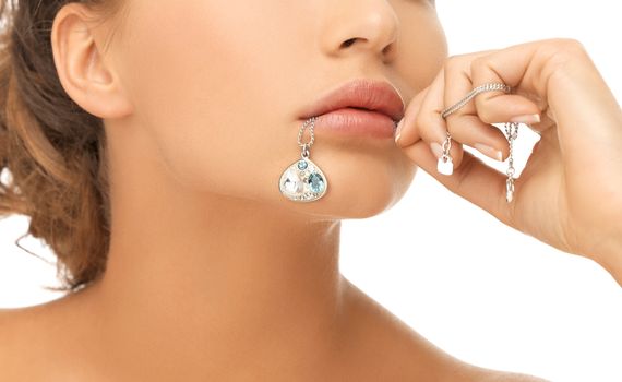 bride and wedding concept - beautiful woman holding shiny diamond pendant in mouth