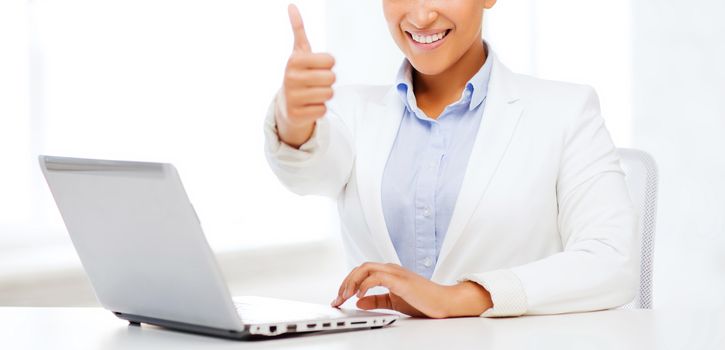 business and technology concept - african businesswoman with laptop in office showing thumbs up