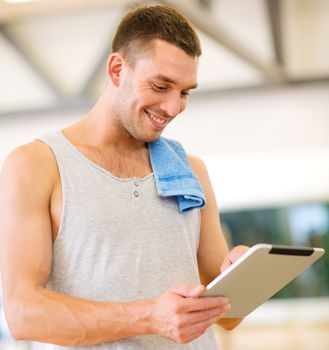 fitness, sport, training, gym, technology and lifestyle concept - young man with tablet pc computer and towel in gym