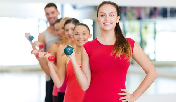 fitness, sport, training, gym and lifestyle concept - group of smiling people lifting dumbbells in the gym