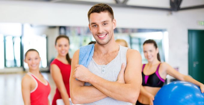 fitness, sport, training, gym and lifestyle concept - smiling man standing in front of the group of people in gym