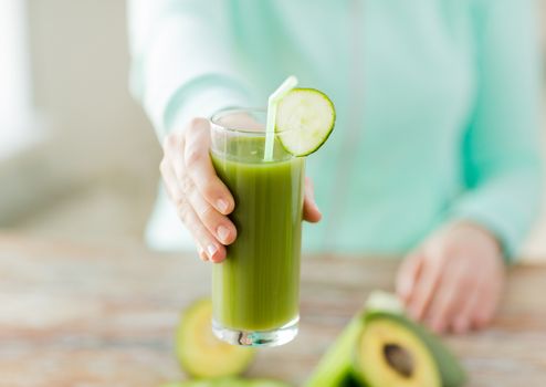 healthy eating, food, dieting and people concept - close up of woman hands with green fresh juice and vegetables sitting at table