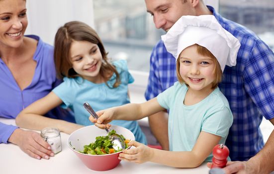 food, children, culinary and people concept - happy family with two kids cooking vegetables at home