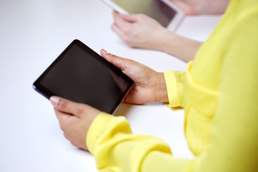 people, technology and internet concept - close up of female hands with tablet pc at table