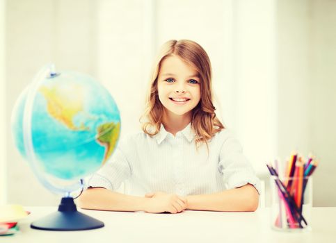 education and school concept - little student girl with globe at school