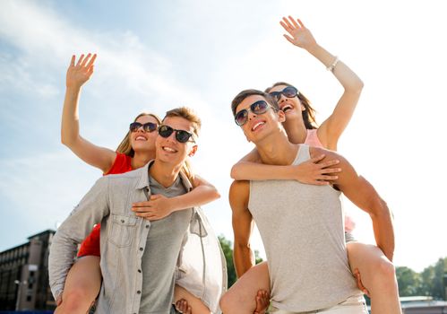 holidays, vacation, love, gesture and friendship concept - smiling couple having fun and waving hands in city