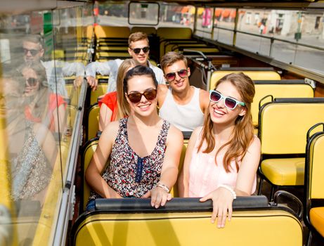 friendship, travel, vacation, summer and people concept - group of smiling friends traveling by tour bus