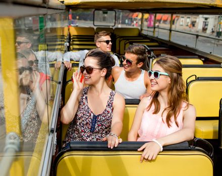 friendship, travel, vacation, summer and people concept - group of smiling friends traveling by tour bus