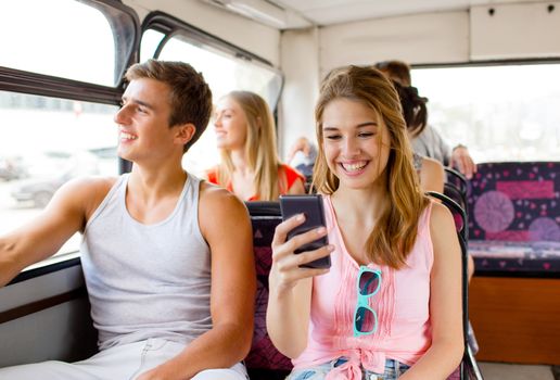 friendship, travel, summer vacation, technology and people concept - smiling couple with smartphone traveling by tour bus and making selfie