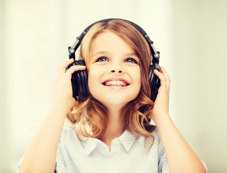 home, technology and music concept - little girl with headphones at home