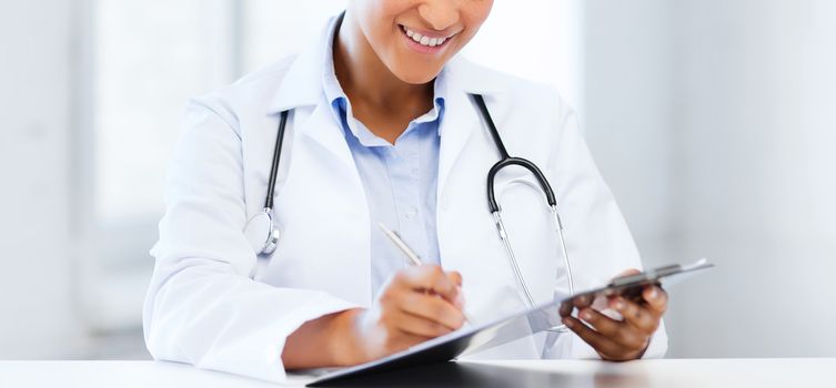 healthcare and medical concept - female doctor with stethoscope writing prescription