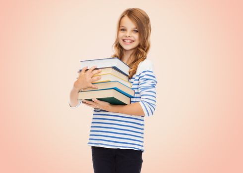 education, people, children and school concept - happy little student girl with many books over beige background