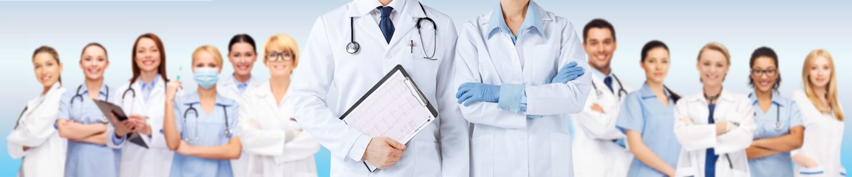 medicine, people, cardiology and health care concept - close up of nurse and male doctor holding cardiogram with medical team over blue background