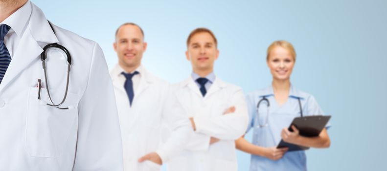 healthcare, profession, teamwork and medicine concept - group of happy medics in white coats over blue background