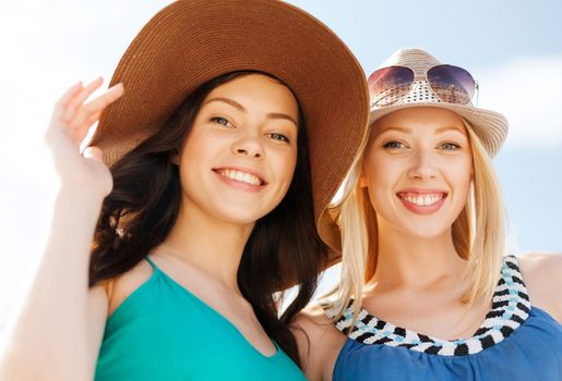 summer holidays and vacation concept - girls in hats on the beach