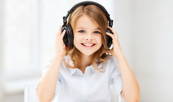 home, technology and music concept - little girl with headphones at home