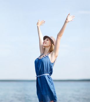 summer holidays and vacation - girl with hands up on the beach