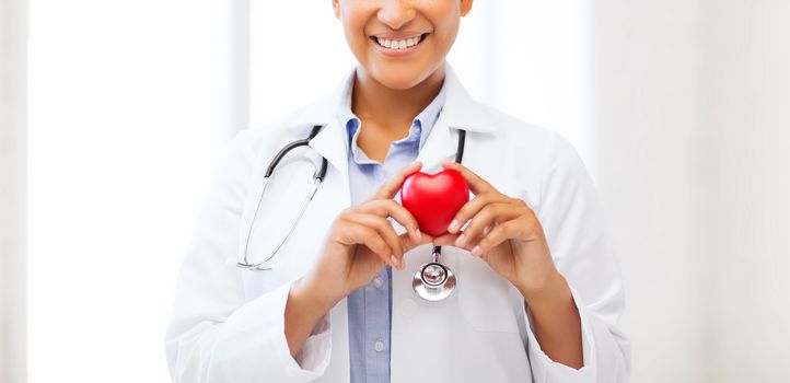 healthcare, medical and cardiology concept - african female doctor with heart