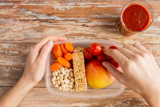 healthy eating, dieting and people concept - close up of woman hands with food in plastic container and fresh tomato juice at home kitchen
