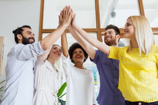 business, startup, gesture, people and teamwork concept - happy creative team making high five in office