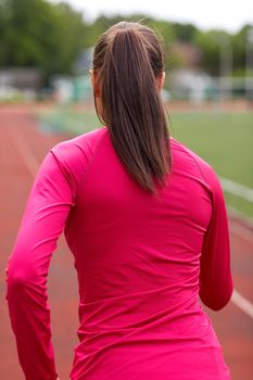 fitness, sport, training, people and lifestyle concept - african american woman running on track outdoors from back