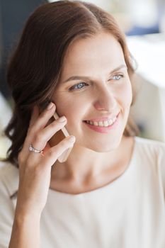 people, women, business and lifestyle concept - happy woman calling on smart phone at restaurant