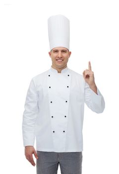 cooking, profession, advertisement and people concept - happy male chef cook pointing finger up to something