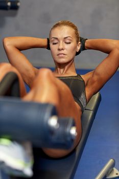fitness, sport, training and lifestyle concept - woman flexing abdominal muscles on bench in gym