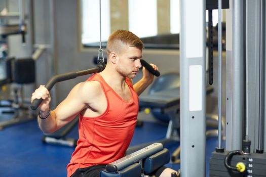 sport, fitness, bodybuilding, lifestyle and people concept - man exercising and flexing muscles on cable machine in gym