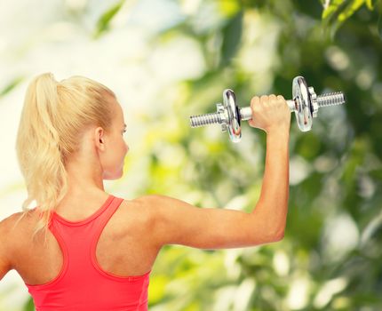 fitness, healthcare and exercise concept - young sporty woman with heavy steel dumbbell from the back