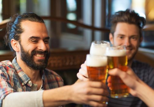 people, men, leisure, friendship and celebration concept - happy male friends drinking beer and clinking glasses at bar or pub