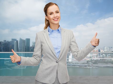 business, education, gesture and people concept - smiling businesswoman showing thumbs up over city background
