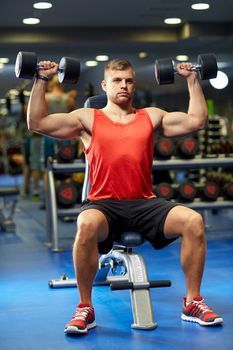 sport, fitness, bodybuilding, lifestyle and people concept - young man with dumbbells flexing muscles in gym