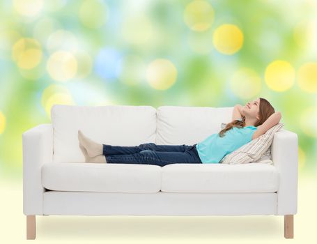 home, leisure, people and happiness concept - smiling little girl lying on sofa and dreaming over green lights background