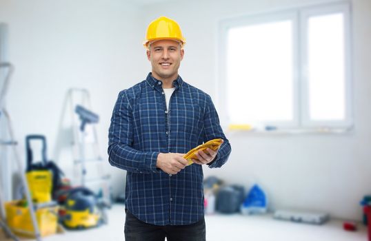 repair, building, construction and maintenance concept - smiling man in helmet with gloves over storeroom background