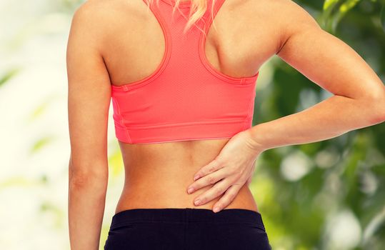 fitness, healthcare and medicine concept - close up of sporty woman touching her back