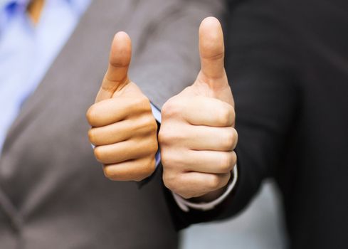 business and office concept - businessman and businesswoman showing thumbs up in office