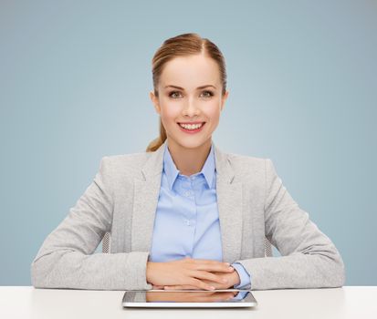 business, technology, education and people concept - smiling businesswoman sitting at table with tablet pc computer over blue background
