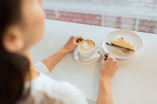 leisure, food and drinks, people and lifestyle concept - close up of young woman hands eating cake and drinking coffee at cafe