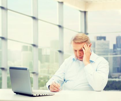 technology, oldness and people concept - senior man with laptop and pen writing over office window background