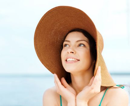 summer holidays and vacation concept - girl in hat standing on the beach