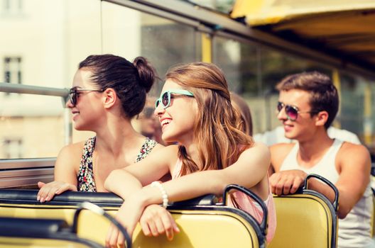 friendship, travel, vacation, summer and people concept - group of smiling friends traveling by tour bus