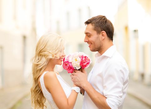 summer holidays, love, relationship and dating concept - couple with bouquet of flowers in the city