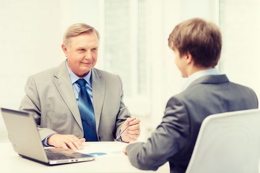 business, technology and office concept - older man and young man having meeting in office