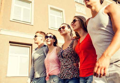 friendship, leisure, summer, gesturer and people concept - group of smiling friends walking in city