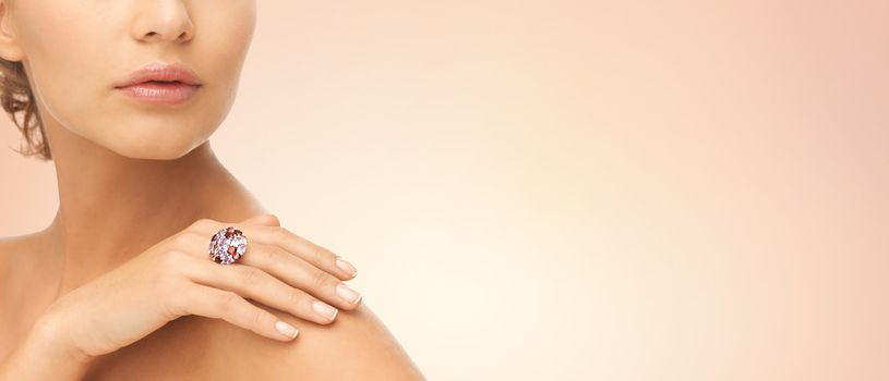 beauty, jewelry, people and accessories concept - close up of woman with cocktail ring on hand over beige background