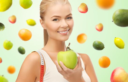 healthy eating, diet, slimming, weight control and people concept - happy young sporty woman with apple and measuring tape over green background with falling fruits